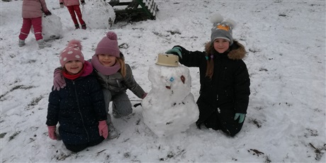 Powiększ grafikę: Zimowe zdjęcie dzieci  na przedszkolnym placu zabaw z bałwankiem