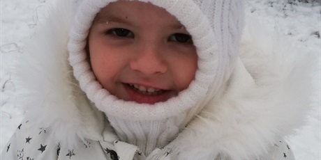 Powiększ grafikę: Uśmiechnięta dziewczynka podczas zabaw zimowych na przedszkolnym placu zabaw