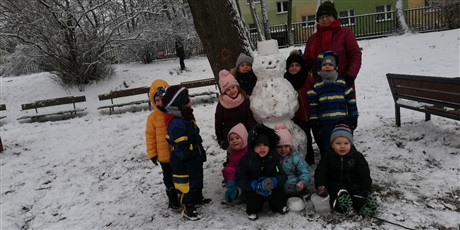 Powiększ grafikę: Zimowe zdjęcie dziecka  na przedszkolnym placu zabaw z bałwankiem