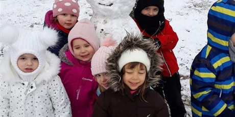 Powiększ grafikę: Dzieci w ieku przedszkolny podczas zimowych zabaw na placu z bałwankiem