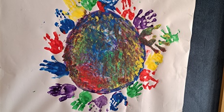 Powiększ grafikę: Na zdjęciu kolorowa duża kropka z odciśniętymi dłońmi dzieci 