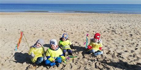 Powiększ grafikę: Na zdjęciu dzieci w żółtych strojach na plaży nad morzem witający wiosnę.