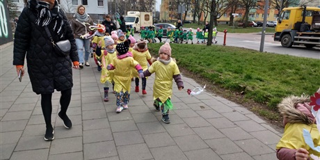 Powiększ grafikę: Na  zdjęciu grupa dzieci w wieku przedszkolnym oraz nauczyciele  w kolorowych strojach  podczas witania pani Wiosny.