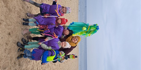 Powiększ grafikę: Na  zdjęciu grupa dzieci w wieku przedszkolnym oraz nauczyciele  w kolorowych strojach  podczas witania pani Wiosny.