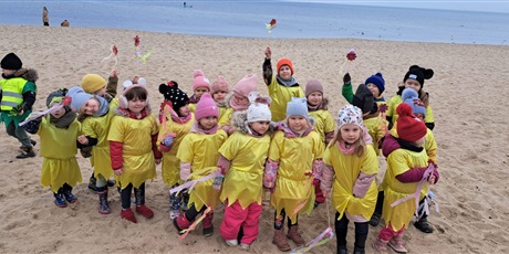 Powiększ grafikę: Na  zdjęciu grupa dzieci w wieku przedszkolnym w kolorowych strojach  podczas witania pani Wiosny.