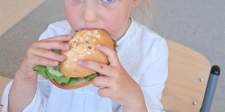 Powiększ grafikę: Na zdjęciu grupa dzieci w wieku przedszkolnym jedząca hamburgery .